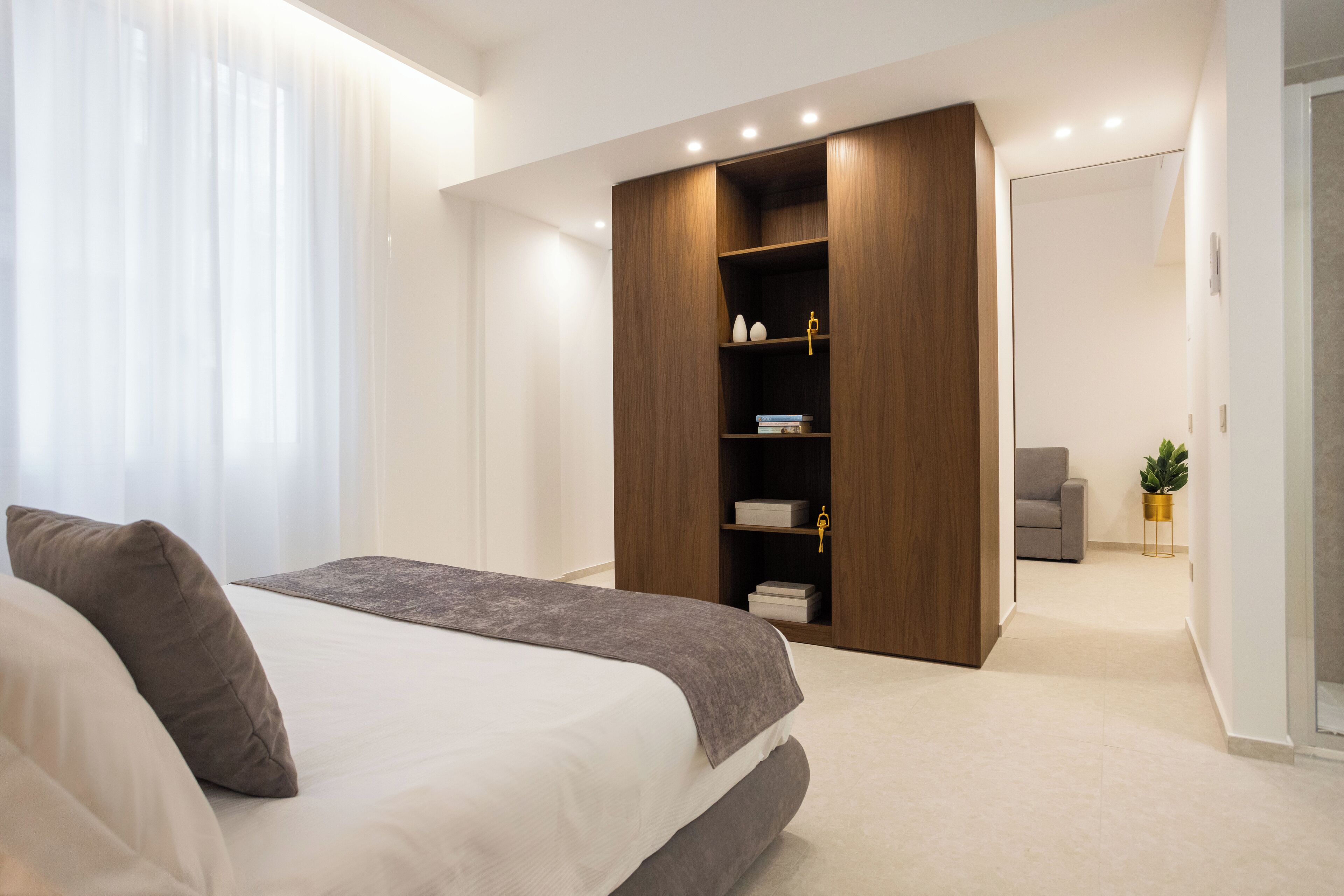 Un dormitorio moderno con una cama grande, un armario empotrado y una pequeña zona de estar.
