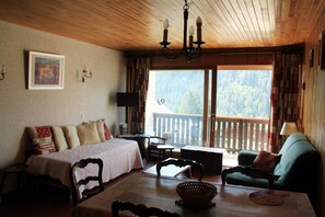A cozy room with a bed, a table, and a chair. There is a window with a view of trees. - Apartment for 5 people with pool (Châtel)