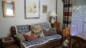A cozy living room with a wooden sofa, a small table, and a chair. - Apartment in Châtel near Aquatic Centre (Châtel)