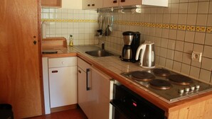 A compact kitchen with a dishwasher, stove, coffee maker, and various utensils. - Apartment only 50 m from the ski slopes (Châtel)