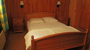 A wooden-paneled bedroom with a bed, nightstands, and wall-mounted lamps. - Apartment only 50 m from the ski slopes (Châtel)