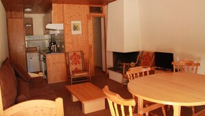 A cozy wooden interior with a sofa, a dining table, and chairs. A small kitchenette is visible in the background. - Apartment only 50 m from the ski slopes (Châtel)