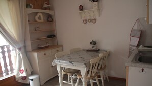 A dining area with a table and chairs, a small shelf with decorative items, and a window with curtains. - Apartment near Ski area in Chatel (Châtel)