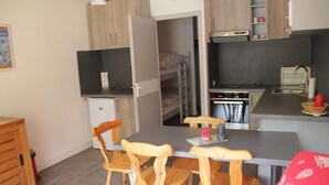 A compact kitchen with a dining table, wooden chairs, a refrigerator, and a microwave. - Apartment in Chatel near cable car (Châtel)