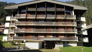 A multi-story hotel with balconies, a flat roof, and a mountainous backdrop. - Apartment in Chatel near cable car (Châtel)