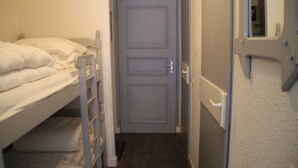 A narrow hallway with a door, a bunk bed with white bedding, and a white wall. - Apartment in Chatel near cable car (Châtel)