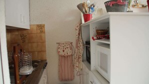 Cuina amb fogó, microones i armaris. Hi ha un drap penjat i una cistella damunt la tauletta.