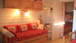 Una habitació acollidora amb un sofà de fusta, una taula petita i un armari.