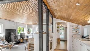 Amplia sala de estar con chimenea, vigas de madera y vistas al exterior.
