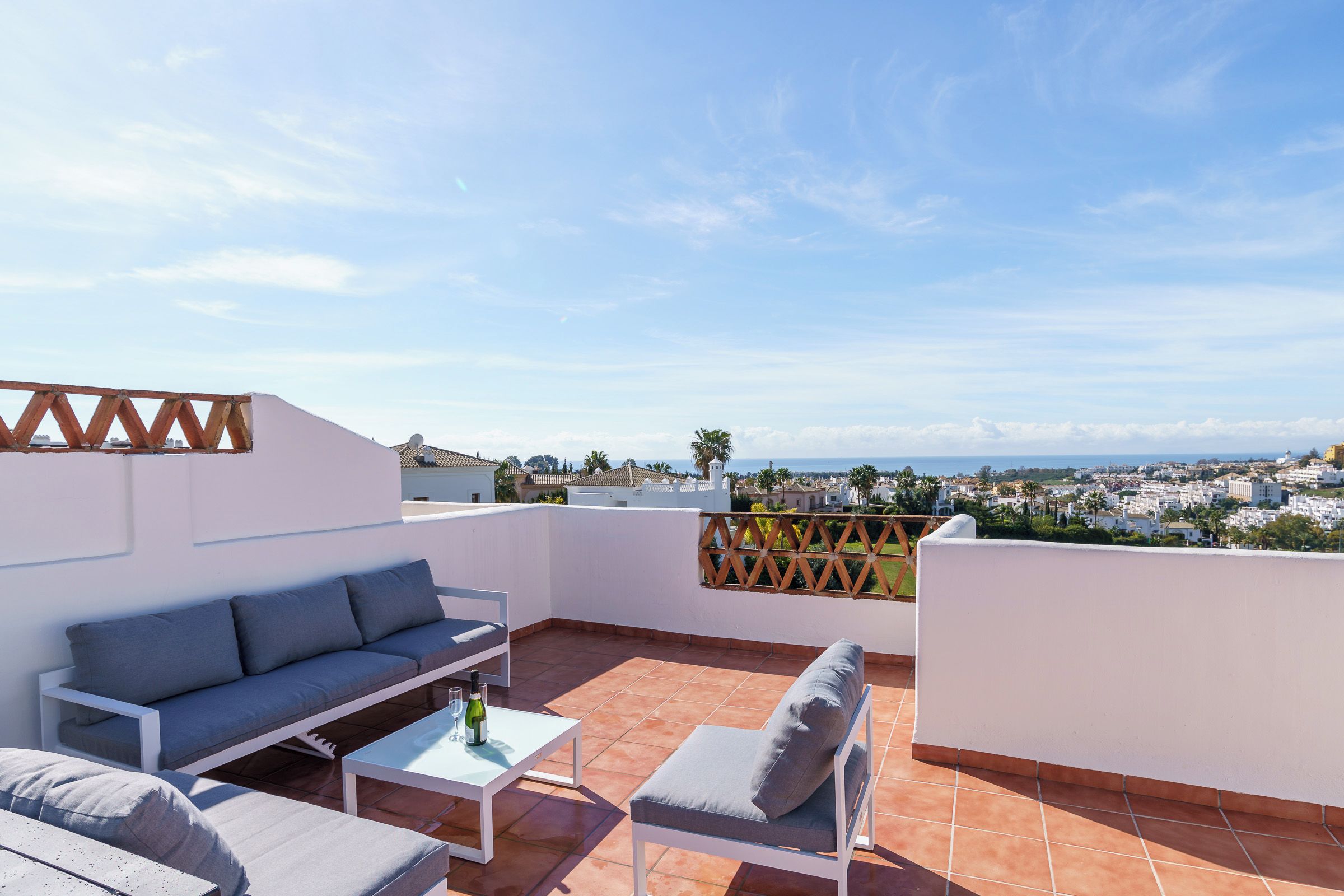 A rooftop terrace with a sofa, a table, and a chair.