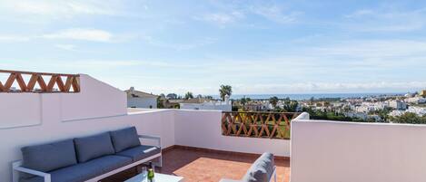 A rooftop terrace with a sofa, a table, and a chair.