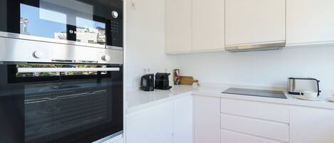 A modern kitchen with white cabinetry, a built-in oven, a coffee maker, and a toaster.