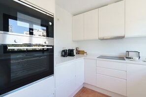A modern kitchen with white cabinetry, a built-in oven, a coffee maker, and a toaster. - Luxe Golf & Family House Escape (Estepona)