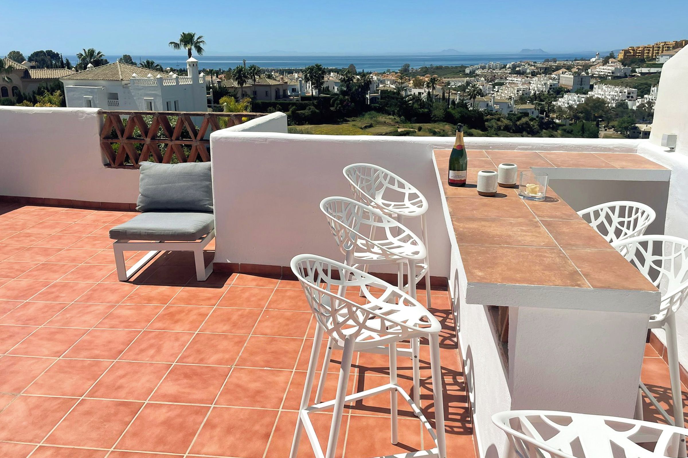 Terraço no telhado com móveis brancos, uma mesa e uma garrafa de champanhe.