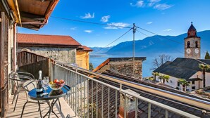 A balcony with a table, chairs, and a bottle of wine. - Bel Panorama 2 Ronco Sopra Ascona (Ronco sopra Ascona)