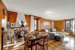 Moderni olohuone, jossa on takka, ruokailutila ja sohva.