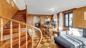 A spacious living area with a wooden staircase, a checkered floor, a sofa, and a dining area with chairs and a table. - Bel Panorama 2 Ronco Sopra Ascona (Ronco sopra Ascona)