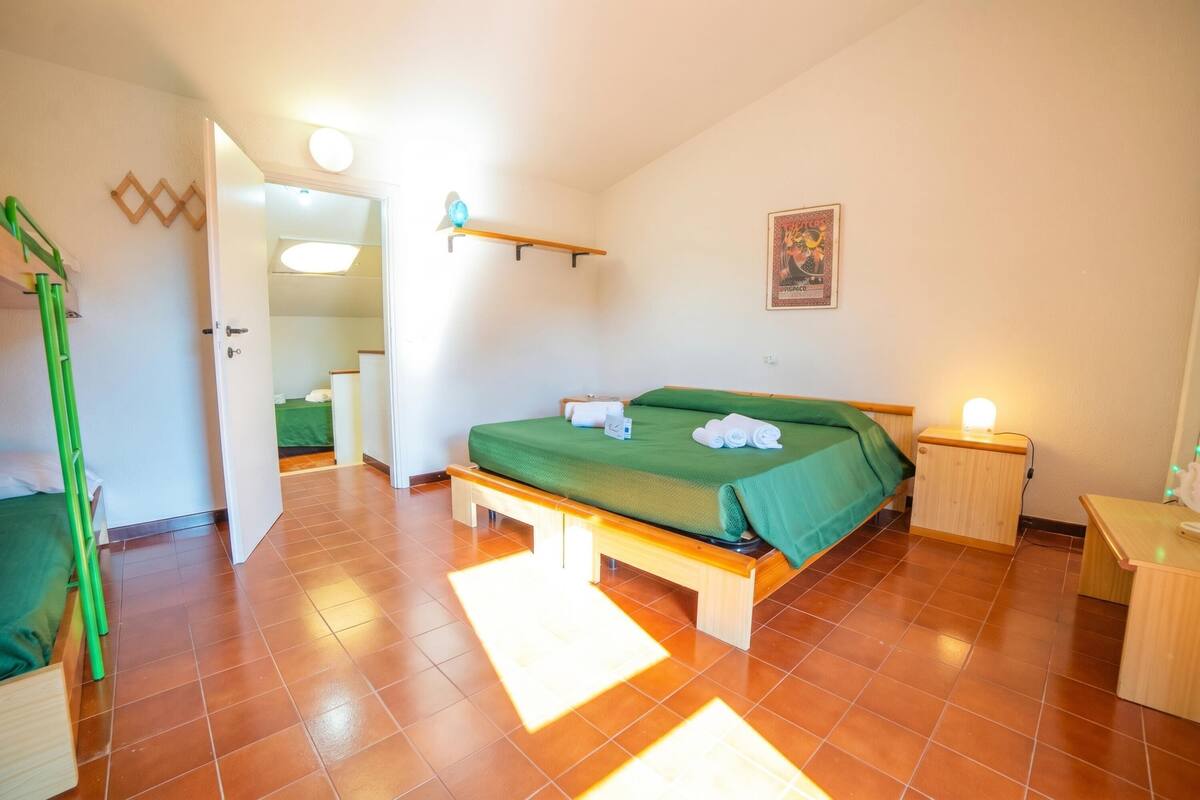 A bedroom with a bed, bedside table, and a green bench.