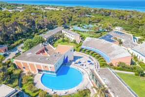 An aerial view of a resort with a central pool, multiple buildings, and surrounding greenery. - Villa 1 Sunset with Pool on Seashore (Otranto)