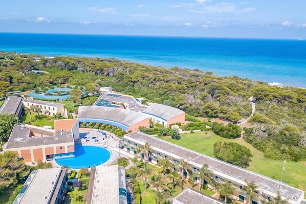 Een resort met een groot zwembad, meerdere gebouwen en uitzicht op de oceaan.