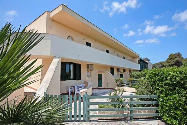 A multi-story building with a flat roof, a staircase leading to the upper floor, and a small outdoor seating area with a table and chairs. - Villa 1 Sunset with Pool on Seashore (Otranto)