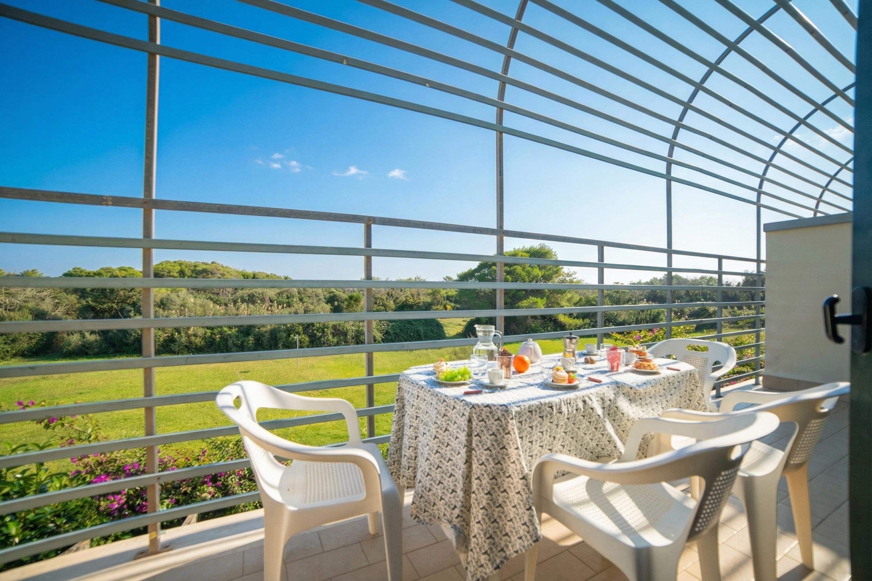 Varanda com mesa posta para dois, com vista para uma paisagem verde.