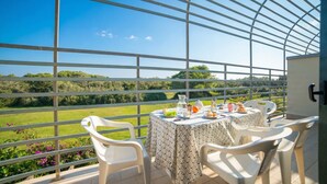 Un balcone con un tavolo apparecchiato per due, affacciato su un paesaggio verde.