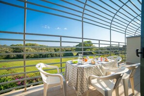 A balcony with a table set for two, overlooking a green landscape. - Villa 1 Sunset with Pool on Seashore (Otranto)