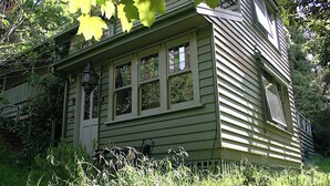 A two-story house with a porch, large windows, and a chimney.