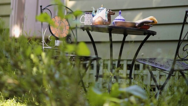 A house with a front porch, a table with chairs, and a hanging lantern.