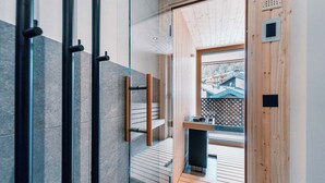 A modern interior with a glass partition, wooden flooring, and a view of a building outside.