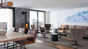 A modern living room with a stone fireplace, leather furniture, and a large window.