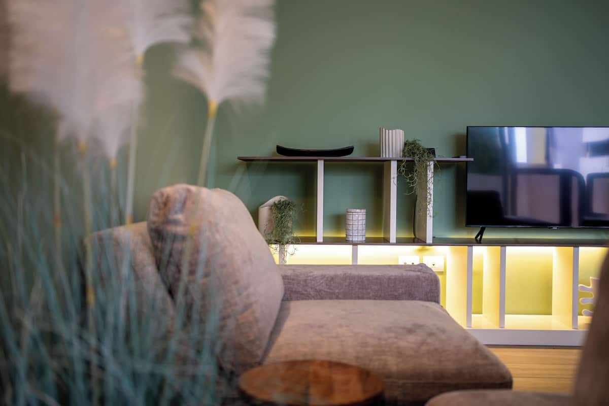 A modern living room with a sofa, a coffee table, and a flat-screen TV mounted on the wall.