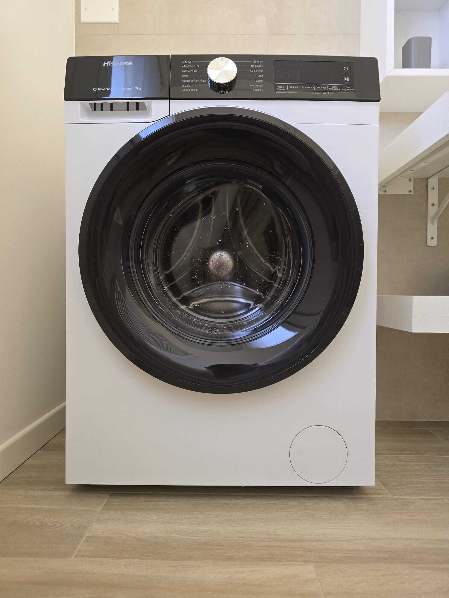 Una lavadora Hisense de carga frontal en una cocina moderna con piso de madera.