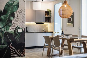 Een moderne keuken met witte kasten, een houten eettafel en een hanglamp.