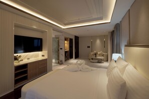 A modern hotel room with a large bed, a flat-screen TV, a marble accent wall, a seating area with a table and chairs, and a bathroom with a shower and toilet. - LA PLANTE SIEM REAP (Siem Reap)