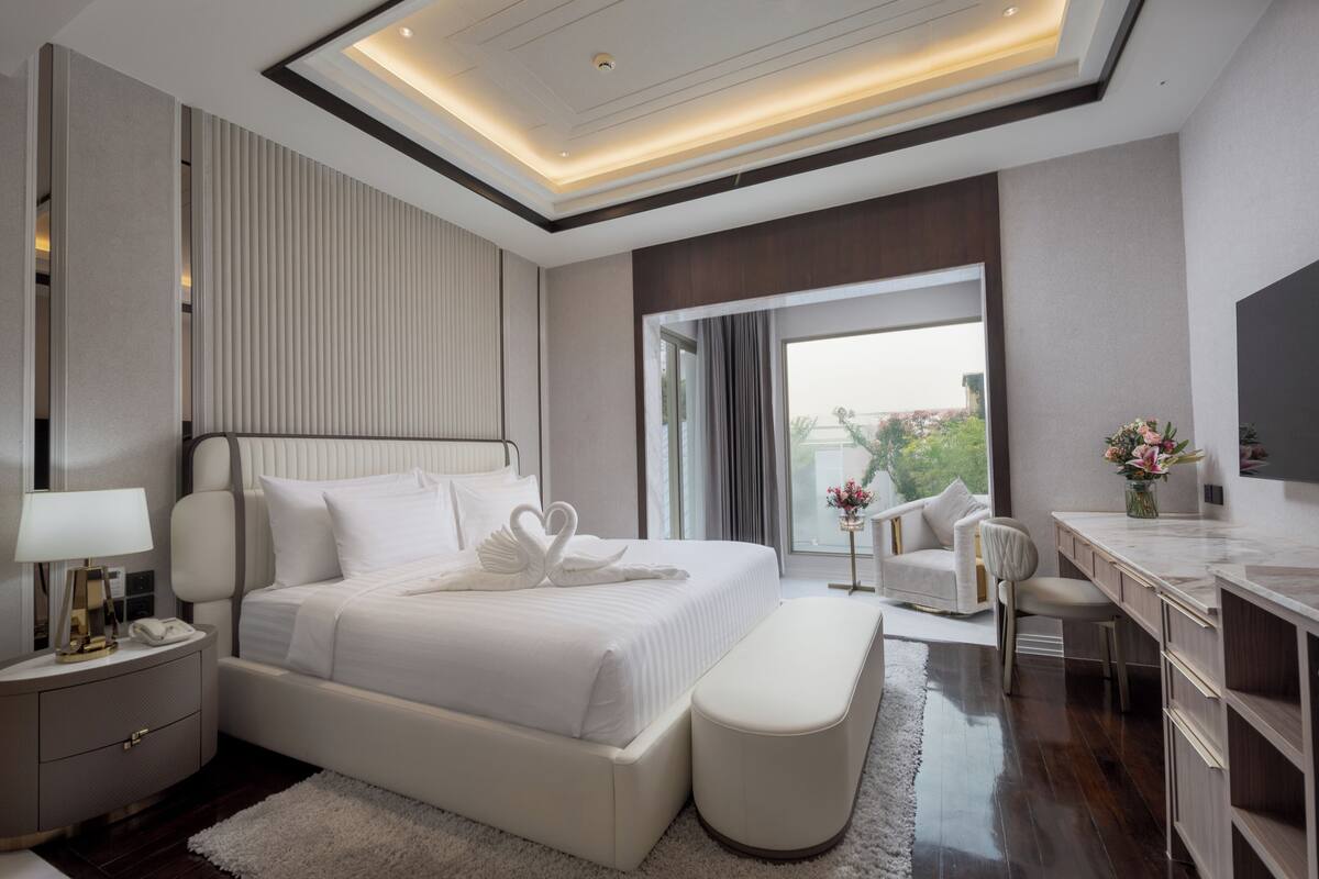 A modern hotel bedroom with a large bed, a desk, and a view of the outdoors.