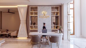 A modern hotel lobby with a reception desk, seating area, and a large window providing natural light. - LA PLANTE SIEM REAP (Siem Reap)