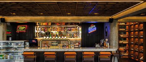 A bar area with a counter, stools, and shelves of bottles.