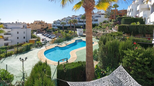 A swimming pool surrounded by greenery and residential buildings. - Riviera Golf Apartment - Pool Views!  - Pass the Keys (Urbanización Riviera Sol)