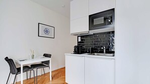A compact kitchen with white cabinets, a microwave, and a coffee maker. - Charming studio - 2P- Nanterre (Nanterre)