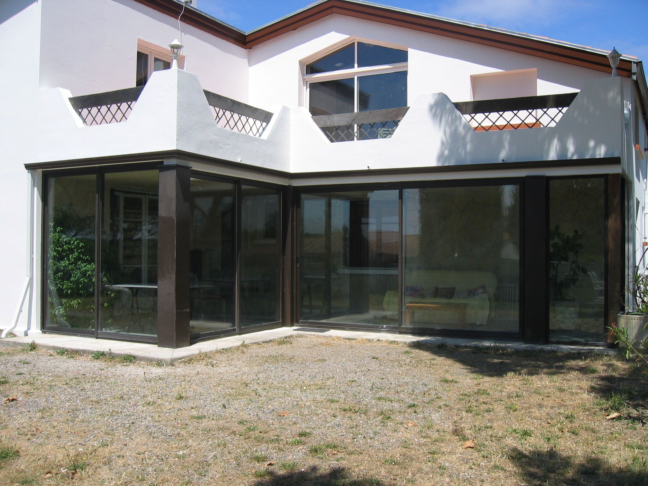 A modern house with a large glass door entrance, a covered patio area, and a sloped roof.