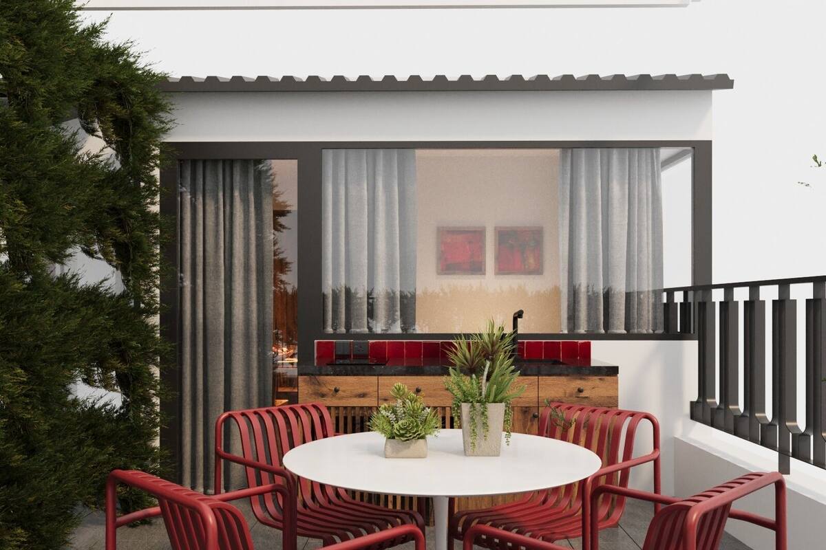 A round table with six red chairs, a white tablecloth, and a potted plant in the center.