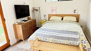 Un dormitorio con una cama, un televisor, un aparador de madera y una ventana.