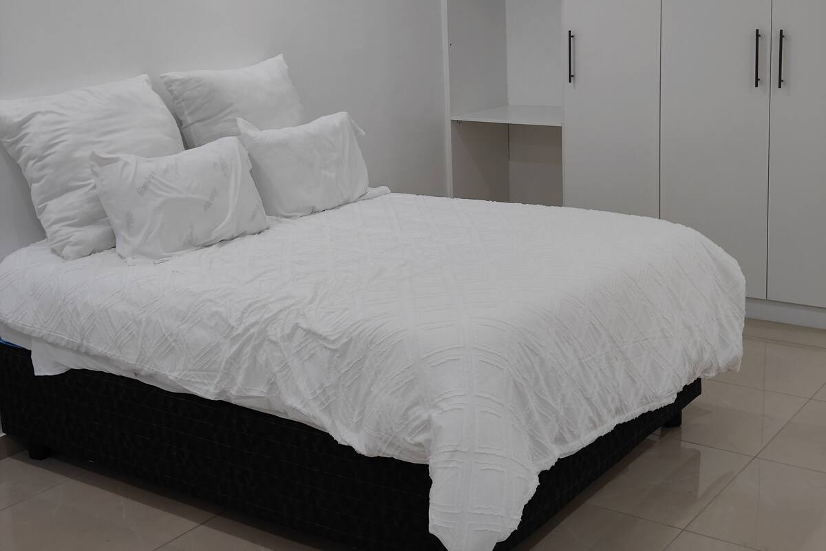 Ein Schlafzimmer mit einem Bett, weißer Bettwäsche und einem Schrank mit mehreren Türen.