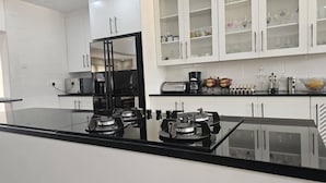 Cocina moderna con electrodomésticos negros, armarios blancos y salpicadero de vidrio.