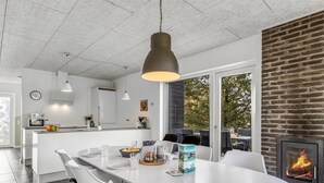 Een moderne keuken met witte kasten, een centraal eiland en een eethoek met witte stoelen.