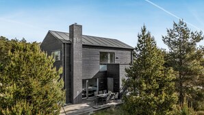 Een modern huis met twee verdiepingen, een groot terras en een schoorsteen.