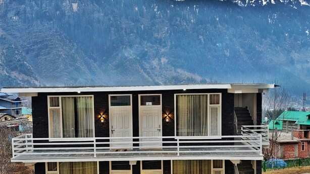 Un immeuble de deux étages doté d’un balcon, de grandes fenêtres et d’un escalier menant à l’étage supérieur.
