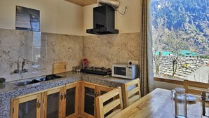 Une cuisine dotée d’un plan de travail en granit, de meubles en bois, d’un four à micro-ondes et d’une fenêtre offrant une vue sur la montagne.